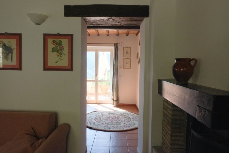 Interior of a farmhouse with natural light illuminating simple, functional furnishings. View of the countryside.