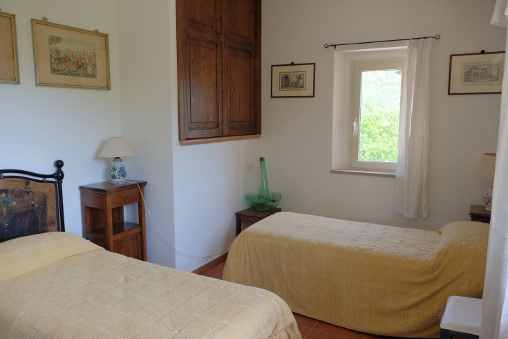 Room with single beds, located inside a building with a view of a green area.