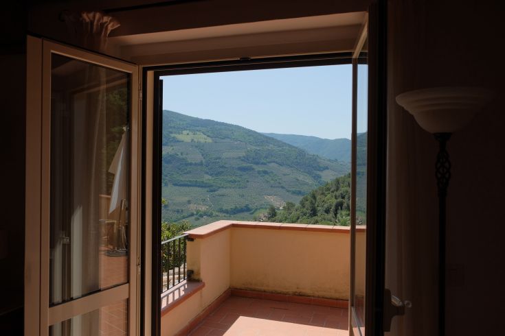 View of Umbrian green hills from the balcony of a historic building in Umbria.