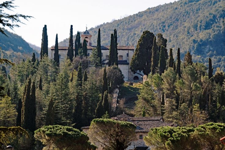 A historic building nestled in nature, surrounded by olive groves and greenery in the serene landscape of Valnerina.