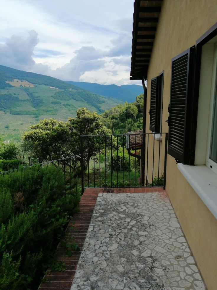 Landscape view from a farmhouse in the countryside, surrounded by lush greenery and gentle hills.