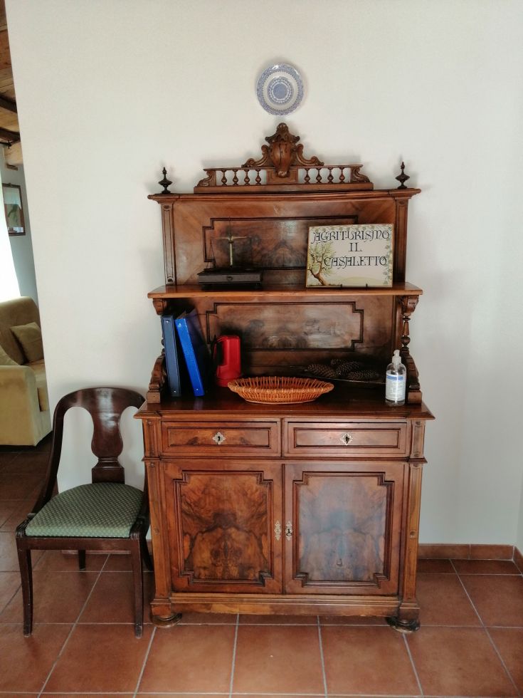 Vintage wooden dresser adorned with decorations, surrounded by books and various items on a shelf.