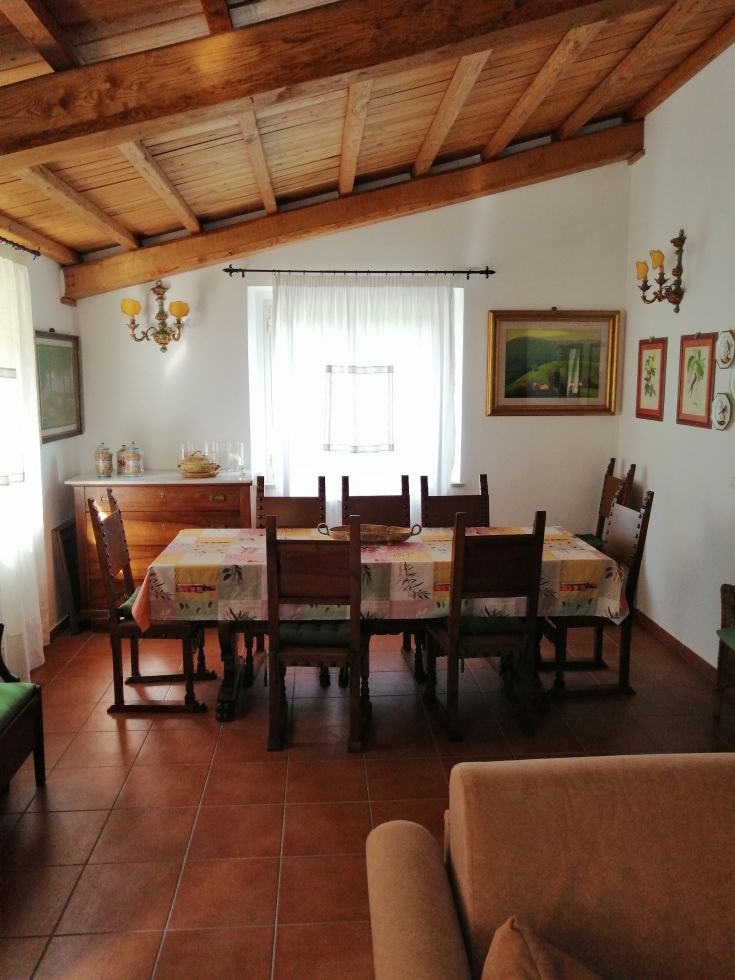Spacious dining room with a long wooden table and exposed wooden beams, perfect for meals with company.