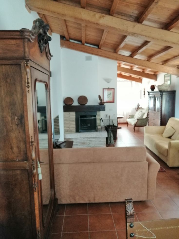 A traditional living room featuring wooden beam ceilings, furnished with antique furniture and modern comforts.