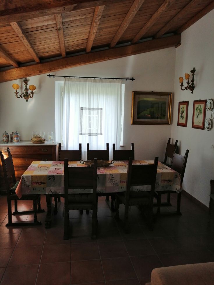 A comfortable dining room featuring a large table and exposed wooden beams. Simple yet elegant decor.