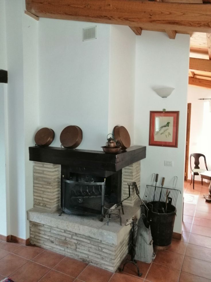 A simple masonry fireplace, adorned with functional copper utensils and objects.