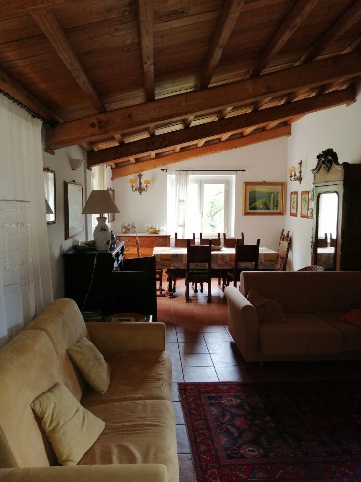 A simple room in a farmhouse with exposed wooden beams and a dining table set for meals.