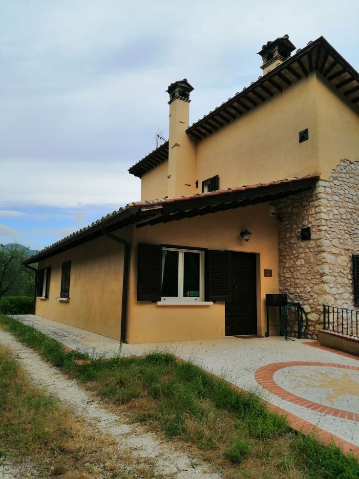 A cozy renovated farmhouse in the Umbrian countryside, surrounded by olive trees.