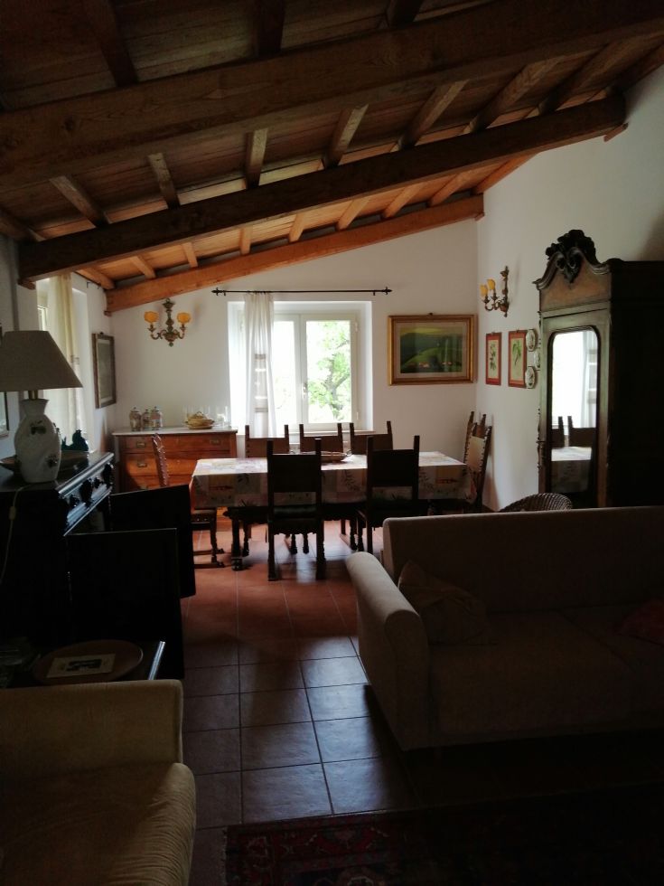 A simple and cozy living room with a wooden table and exposed beams on the ceiling, perfect for gatherings.