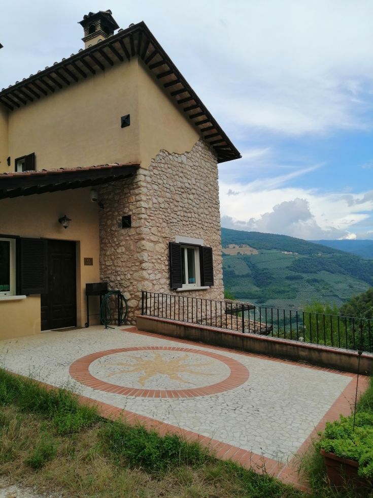 Historic stone building surrounded by trees and olive groves, with a pool nestled in greenery.