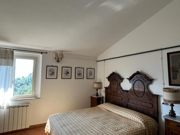 A simple and comfortable room with wooden furniture, overlooking an olive landscape. A quiet corner of Valnerina.