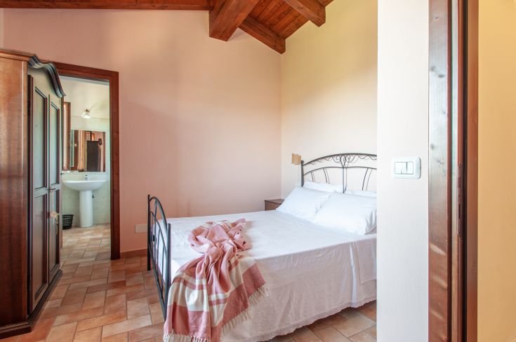 Spazio semplice con letto matrimoniale e mobili in legno, dotato di bagno privato.