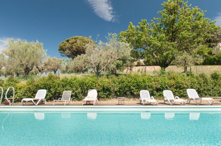 Scena di una piscina in una villa circondata da spazi verdi, perfetta per momenti di relax.