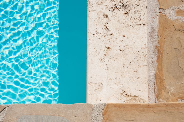 Scena di una piscina con acqua limpida, circondata da un elegante bordo in pietra.