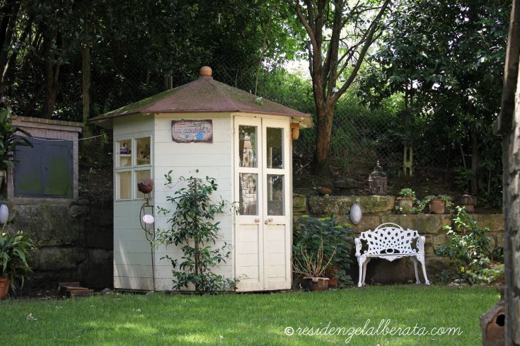 Ampia casetta nel giardino, circondata da piante e alberi, ideale per momenti di relax all'aperto.