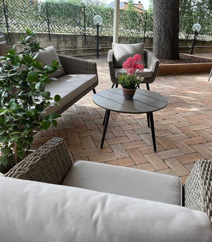 Un'area all'aperto con divani confortevoli e un tavolo, circondata da alberi e vegetazione.