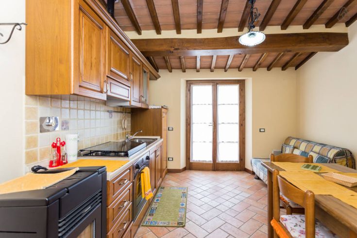 Einfache Holzküche mit traditionellen Details und großen Fenstern, die viel Licht einlassen.