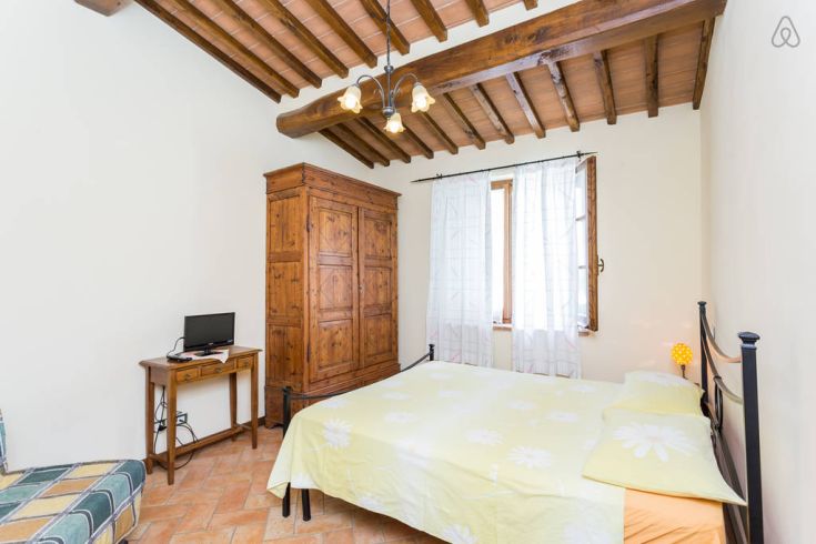 Einfaches Schlafzimmer mit einem Doppelbett, Kleiderschrank und Fernseher, ideal für entspannende Momente.