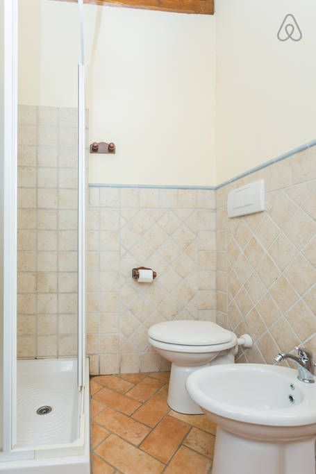 Einfaches Badezimmer mit Dusche, Sanitäranlagen und Fliesen in neutralen Farben.