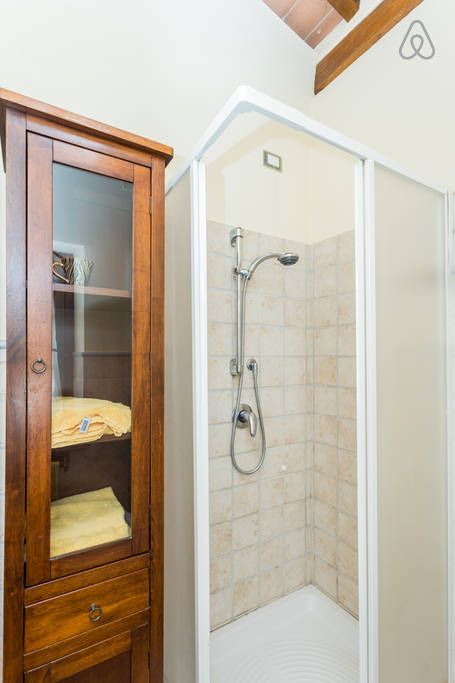 Einfache Dusche in einem modernen Badezimmer mit großen Fenstern und einem hellen Boden.