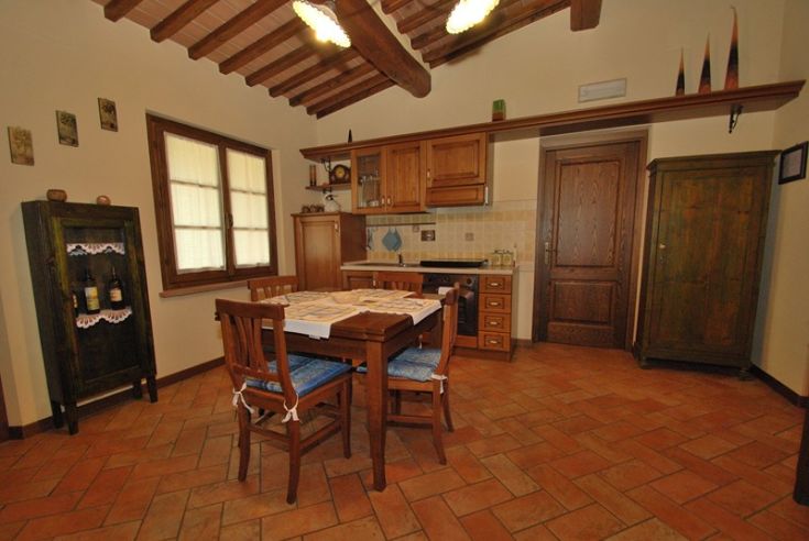 Traditionelle Küche mit einem massiven Holztisch, einem Holzschrank und typischen Dekorationen.