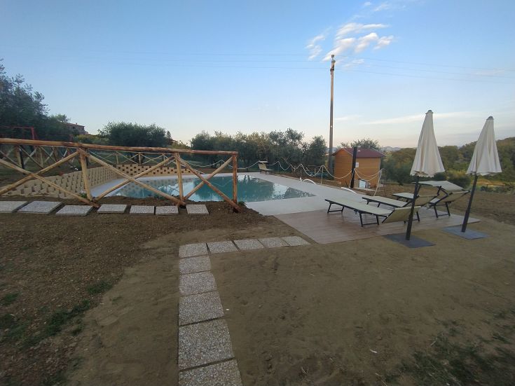 Umgeben von einem Garten mit einem Pool, Entspannungsbereichen und Kinderspielen, perfekt für friedliche Momente.