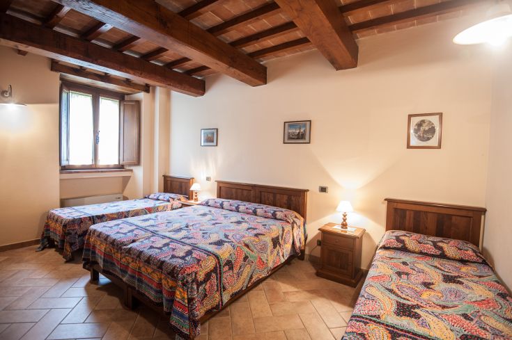 Camera semplice in agriturismo, dotata di letti singoli e matrimoniali. Perfetta per un soggiorno tranquillo.