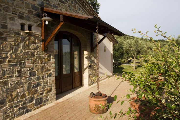 Un edificio in pietra immerso in un paesaggio di giardini e colline, perfetto per una pausa nella natura.