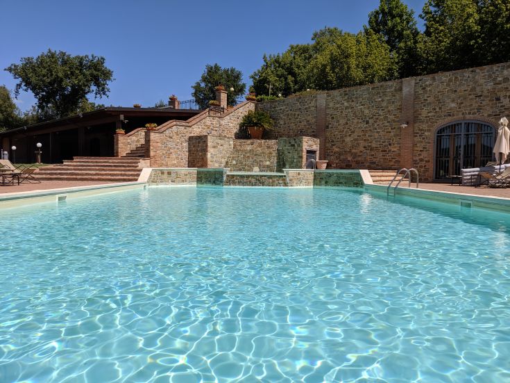 Un agriturismo con piscina immerso in un paesaggio di colline verdi, ideale per momenti di relax e tranquillità.