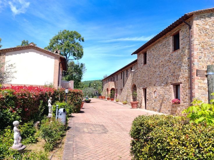Agriturismo immerso nel verde delle campagne umbre, con un edificio tradizionale e spazi esterni curati.