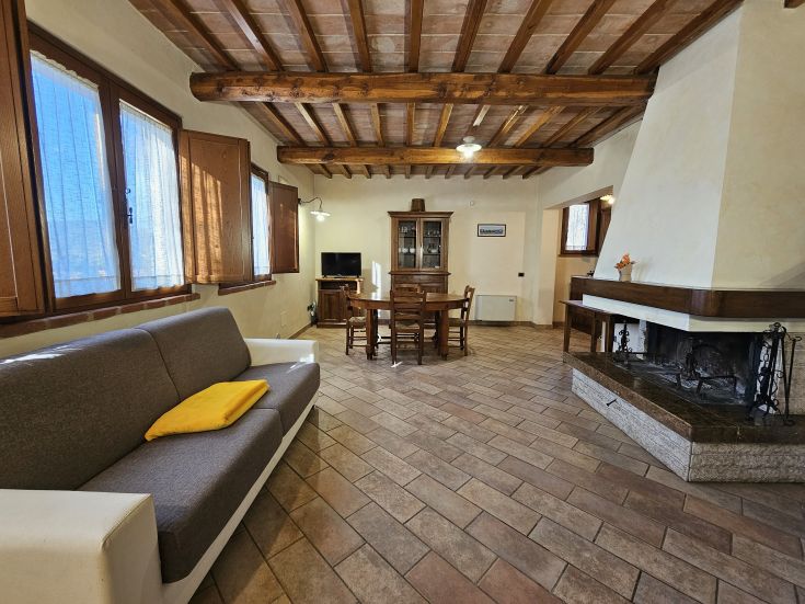 Un soggiorno semplice con un camino e un tavolo da pranzo, tipico di un agriturismo dell'Umbria.