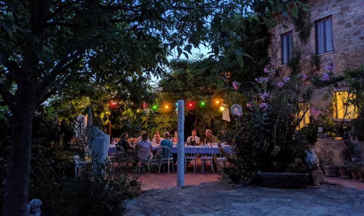 Semplice cena all'aperto in un giardino, con tavoli decorati e luci soffuse, perfetta per una serata estiva.