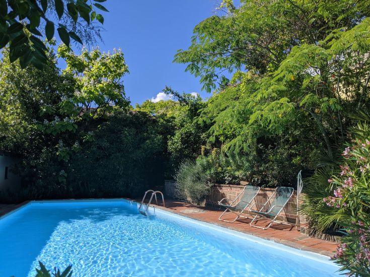 Una piscina circondata da un ampio giardino con alberi e fiori, ideale per momenti di relax.
