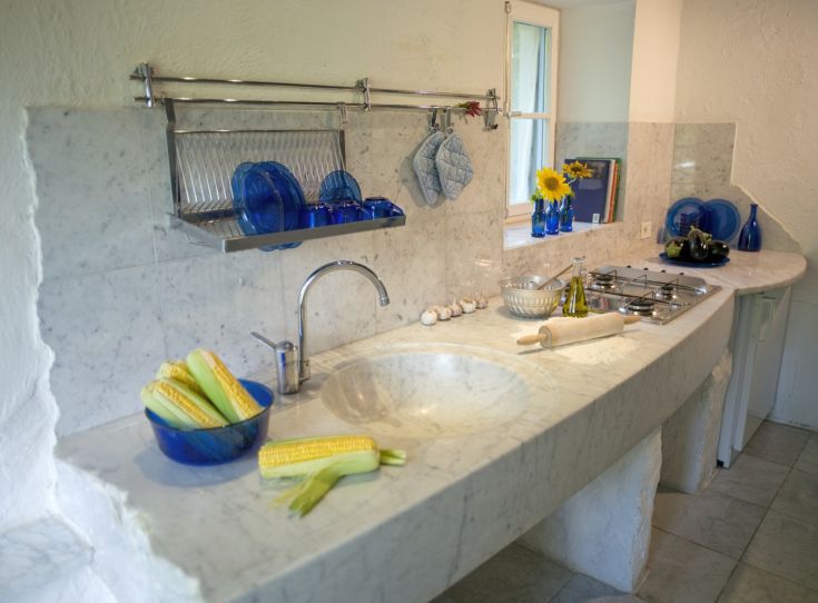 Una cucina ben progettata con un piano in marmo e accessori blu, che comunica calore e accoglienza.