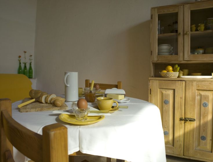 Una tavola ben apparecchiata con piatti gialli e pane fresco, che crea un'atmosfera accogliente.