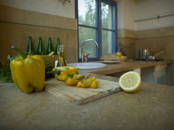 Un'area di cucina con peperoni gialli, limoni freschi e olio d'oliva, pronta per preparare piatti saporiti.