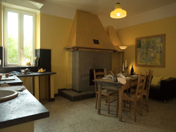 Ambiente luminoso con un tavolo apparecchiato e un camino che conferisce calore alla cucina.