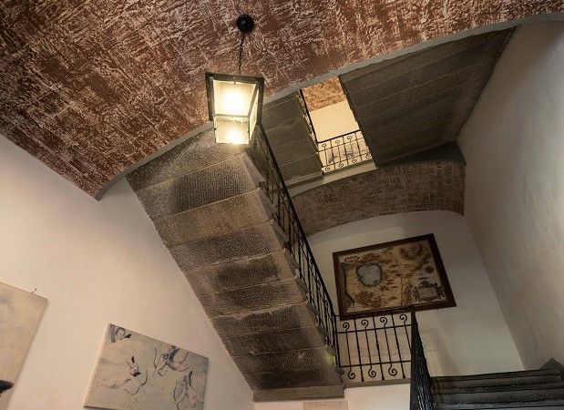 Intérieur d'un bâtiment avec un escalier élégant et un lustre, offrant une ambiance sobre et confortable.