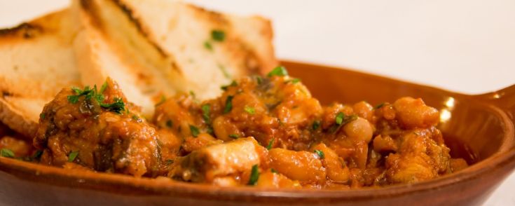 Un plat de ragoût servi avec des tranches de pain grillé et du persil haché.