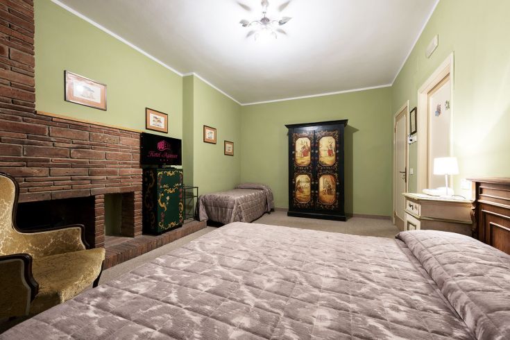 Chambre d'hôtel confortable avec des lits doubles, des décorations traditionnelles et une cheminée. Atmosphère chaleureuse et détendue.