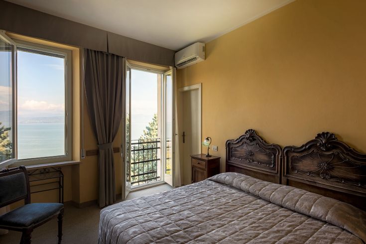 Chambre simple et accueillante avec vue sur le lac, meublée avec des éléments pratiques et de style classique.