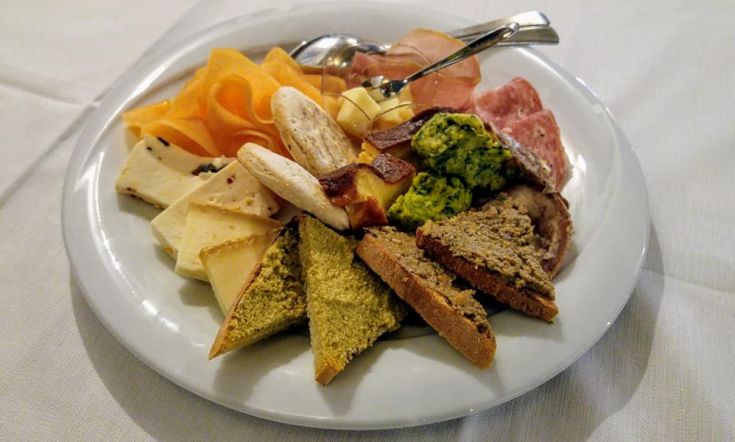 Un plat bien présenté avec une sélection de fromages, de charcuterie et de pain, idéal en tant qu'entrée.