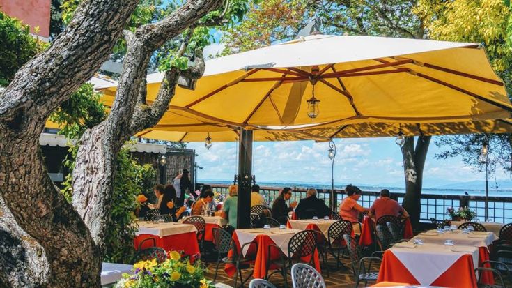 Restaurant en plein air au bord du lac, avec des parasols jaunes et des tables pour un déjeuner paisible.