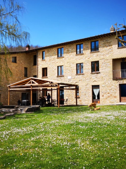 A view of a traditional farmhouse in Umbria, surrounded by lush greenery and nature.