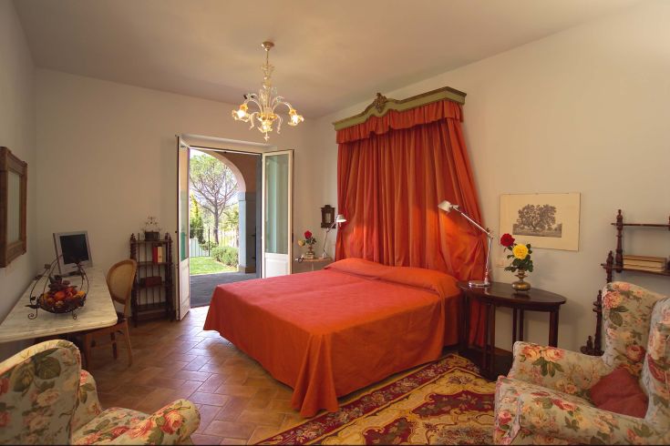 Una camera con letto arancione, arredamento vintage e affaccio su un giardino.