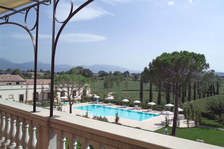 Scena della piscina e del parco della villa, avvolti nel verde in un ambiente tranquillo.