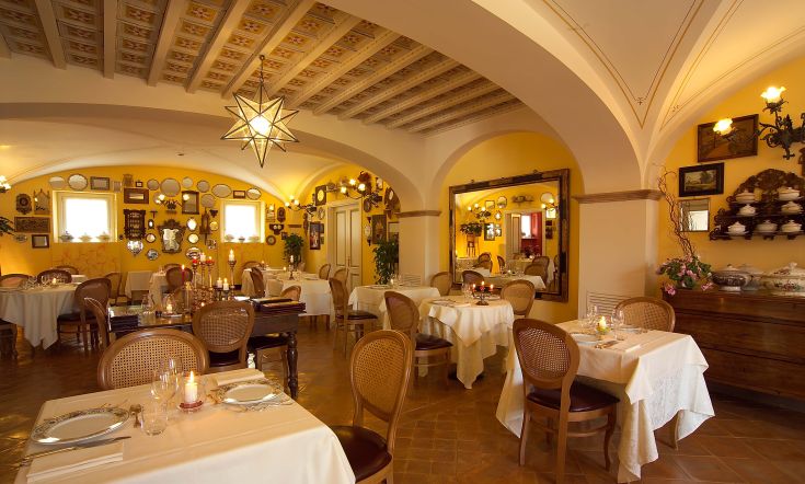 Ristorante semplice con tavoli apparecchiati e decorazioni tradizionali su pareti gialle.