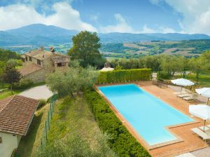 Panorama d'une piscine entourée de collines verdoyantes en Ombrie, idéale pour des moments de détente.