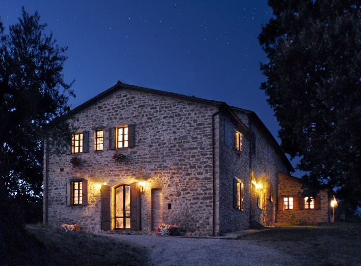 Une maison en pierre illuminée par la lune, située dans un cadre paisible à la campagne.