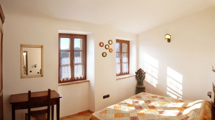 Chambre spacieuse avec des murs clairs, un lit simple et des décorations discrètes qui créent une atmosphère accueillante.